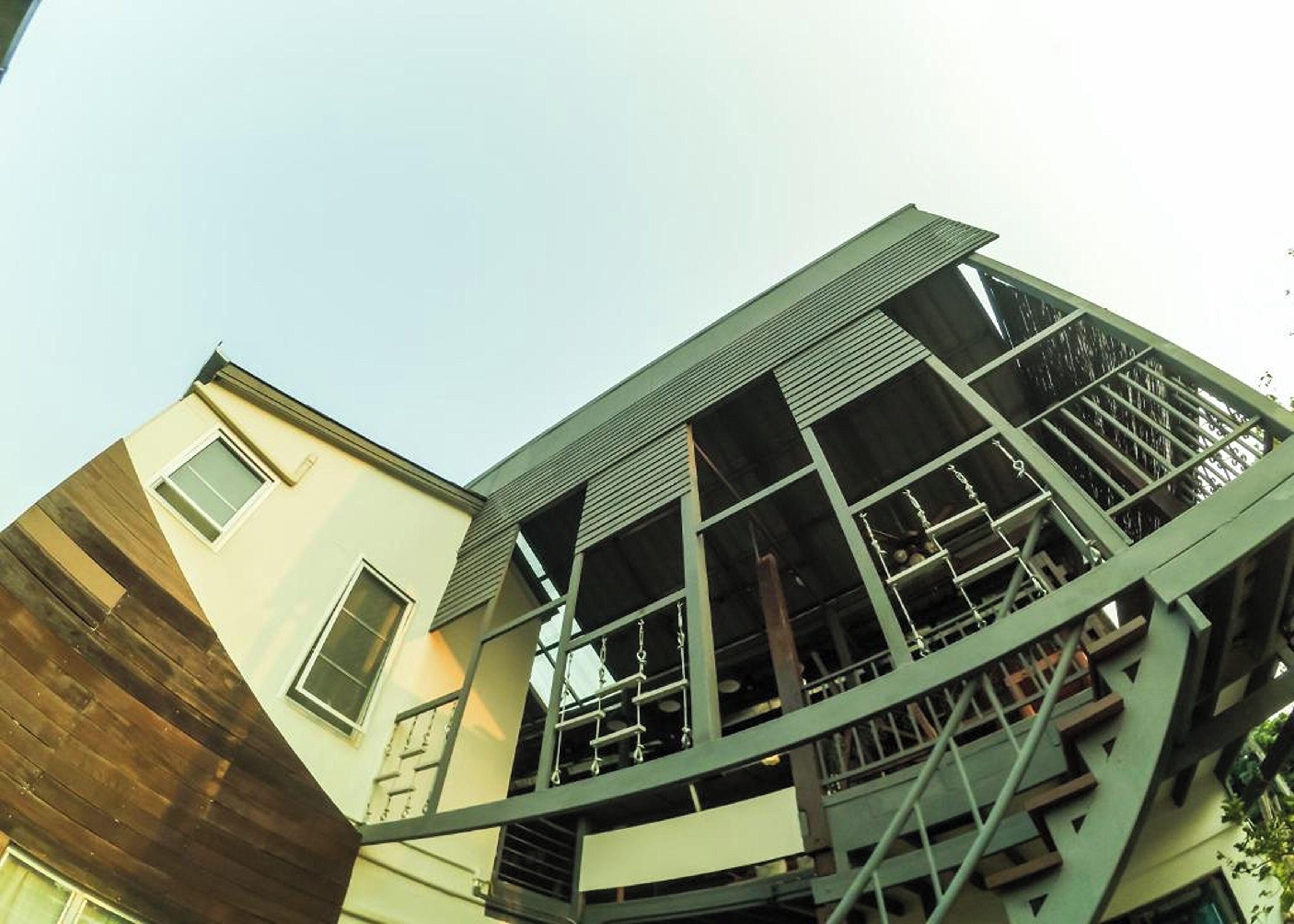 A multi-story building with a green metal framework, large windows, and a mix of wooden and concrete facades.