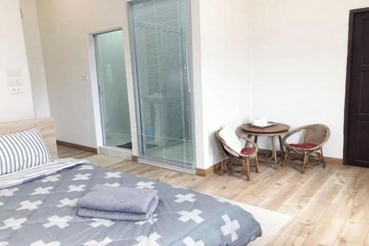 A bedroom with a bed, a small table with chairs, and a sliding glass door leading to a balcony.