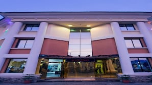 A hotel entrance with a central glass door, columns, and a sign reading "KAPINO". - Kapino Suites (Abuja)
