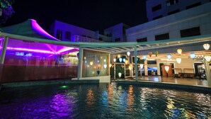 Hotel met zwembad, overdekt buitenzitgedeelte en een goed verlichte entree.
