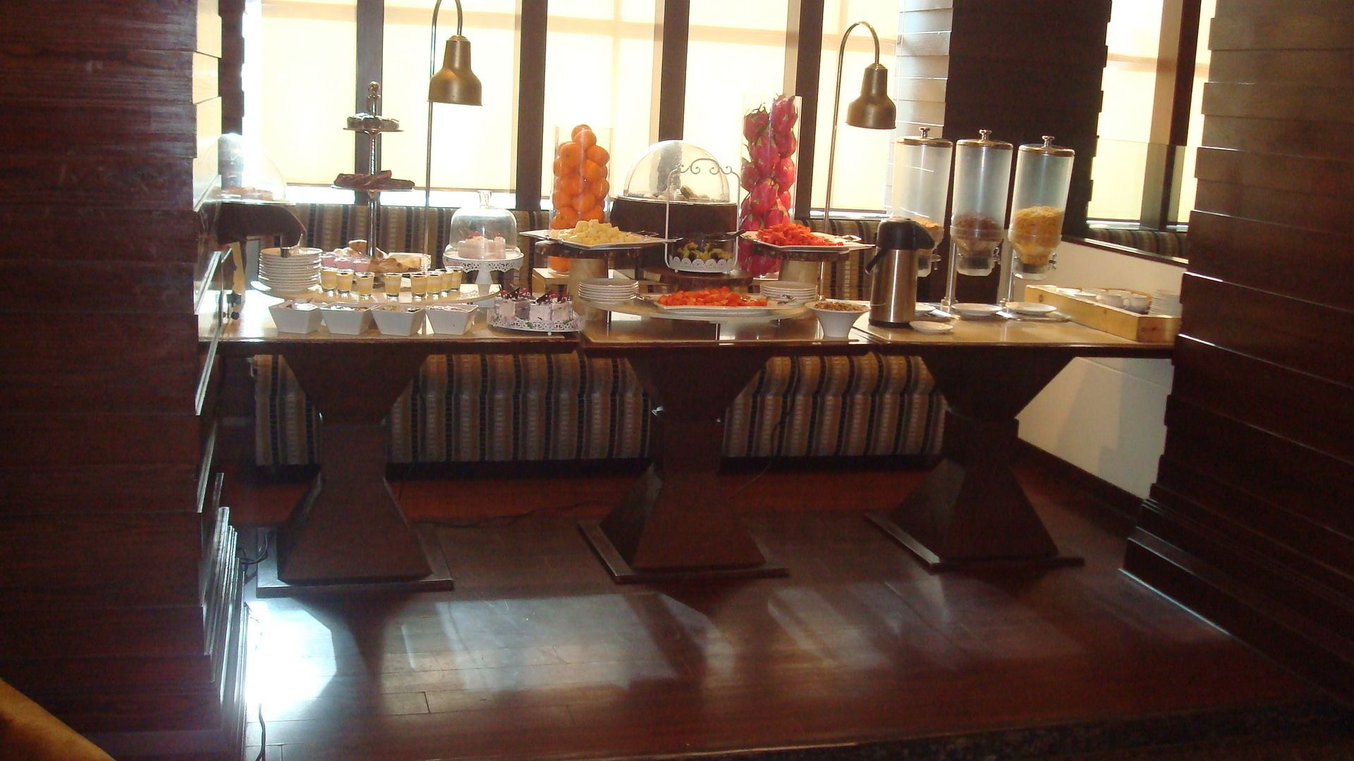 A buffet setup with multiple food stations, cushioned seating, and a wooden floor.