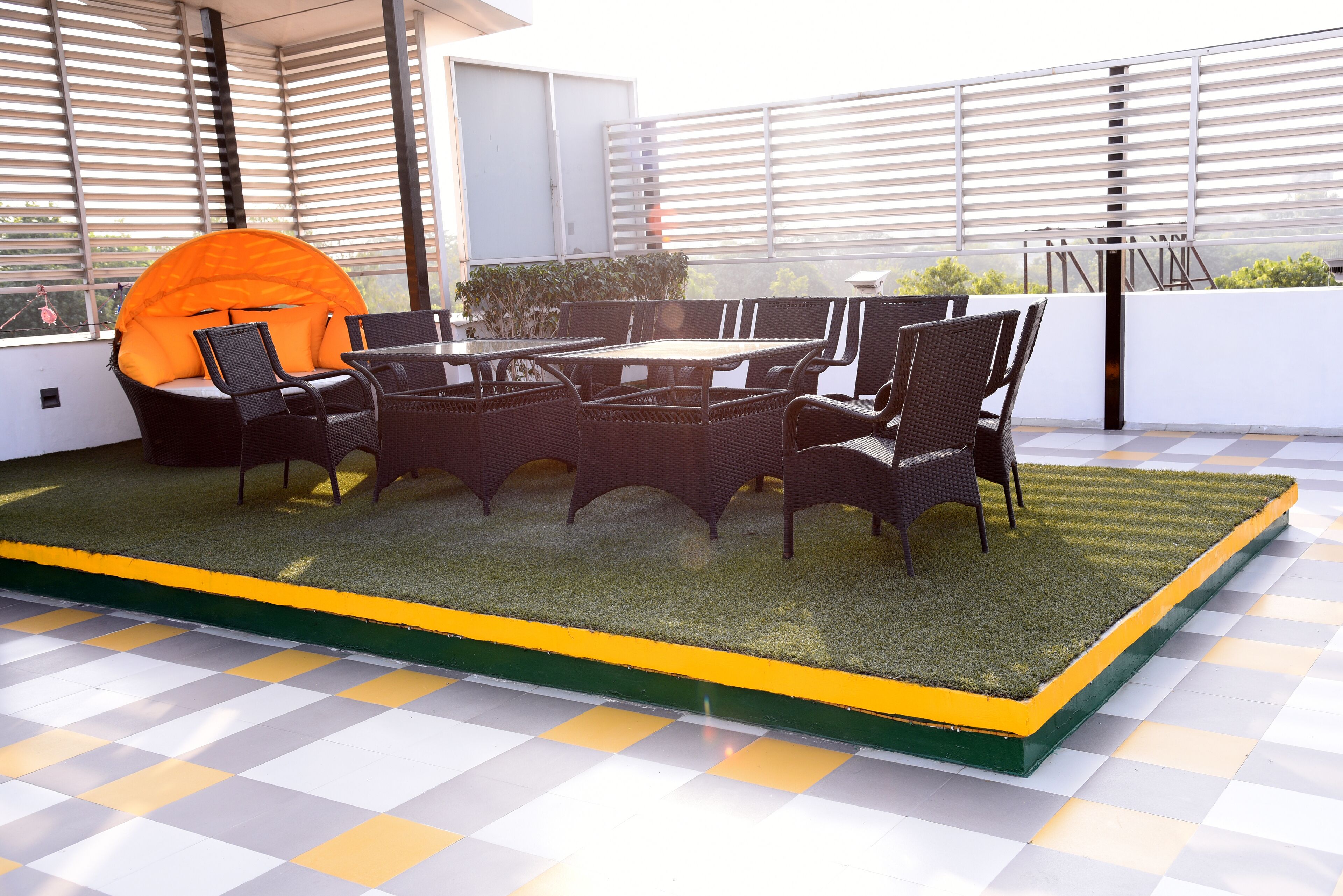 A rooftop terrace with a checkered floor, a round table, and wicker chairs.