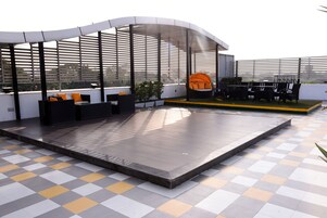 A rooftop terrace with outdoor seating, a covered area, and a checkered floor pattern.