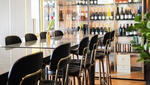 Una zona de bar con una mesa larga, varias sillas y estantes llenos de botellas de vino.