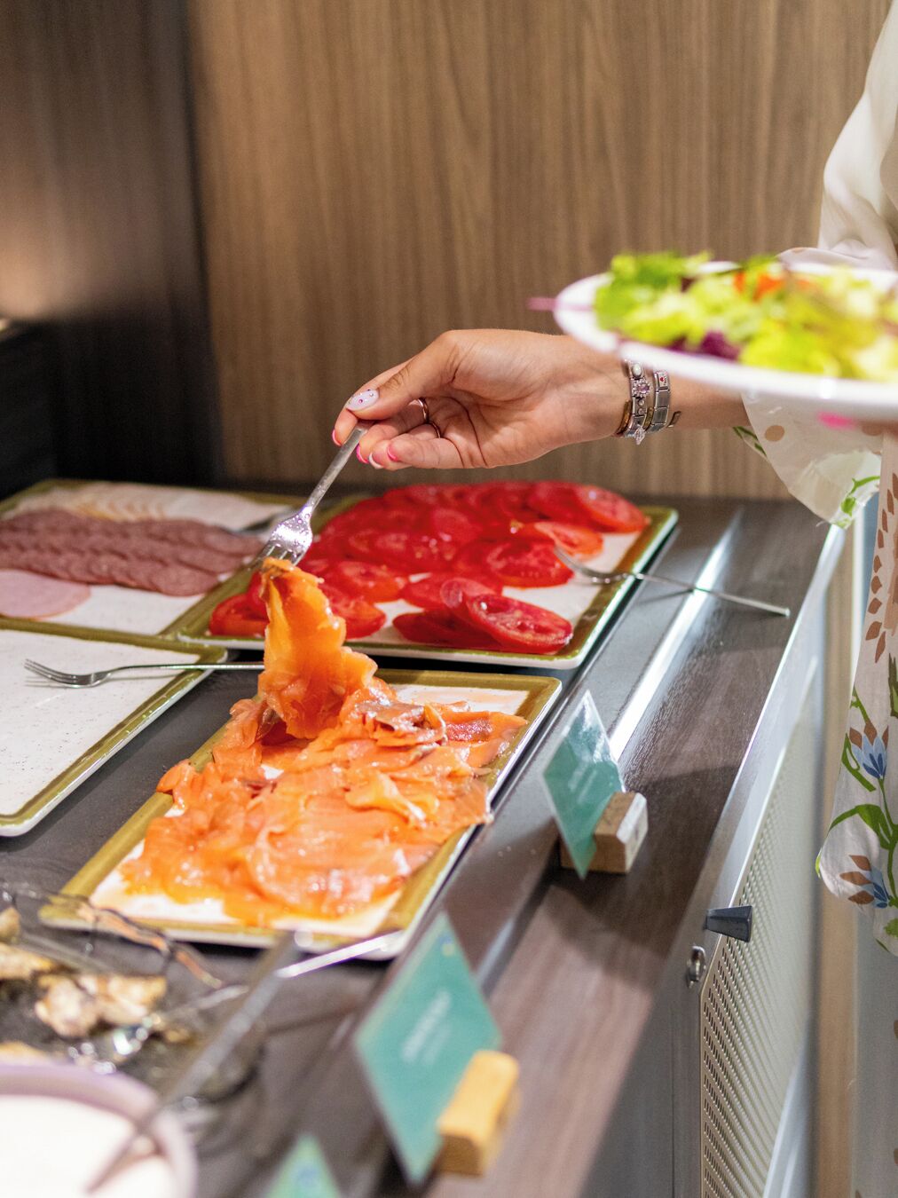 Buffet com diversas opções de comida, incluindo salmão, tomate e salada.