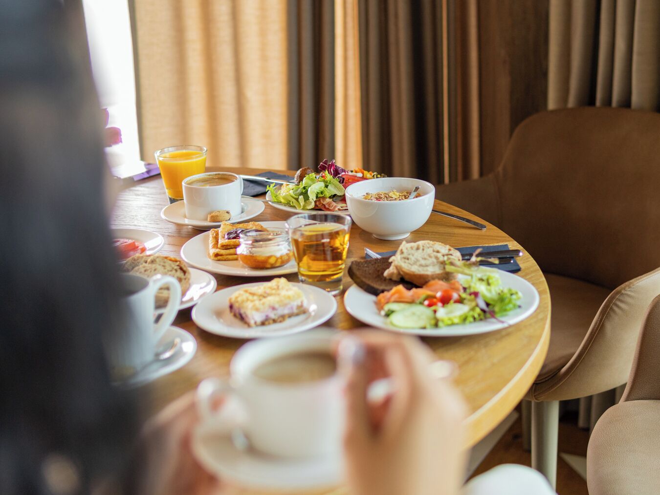 A breakfast setting with a variety of food items and beverages on a wooden table.