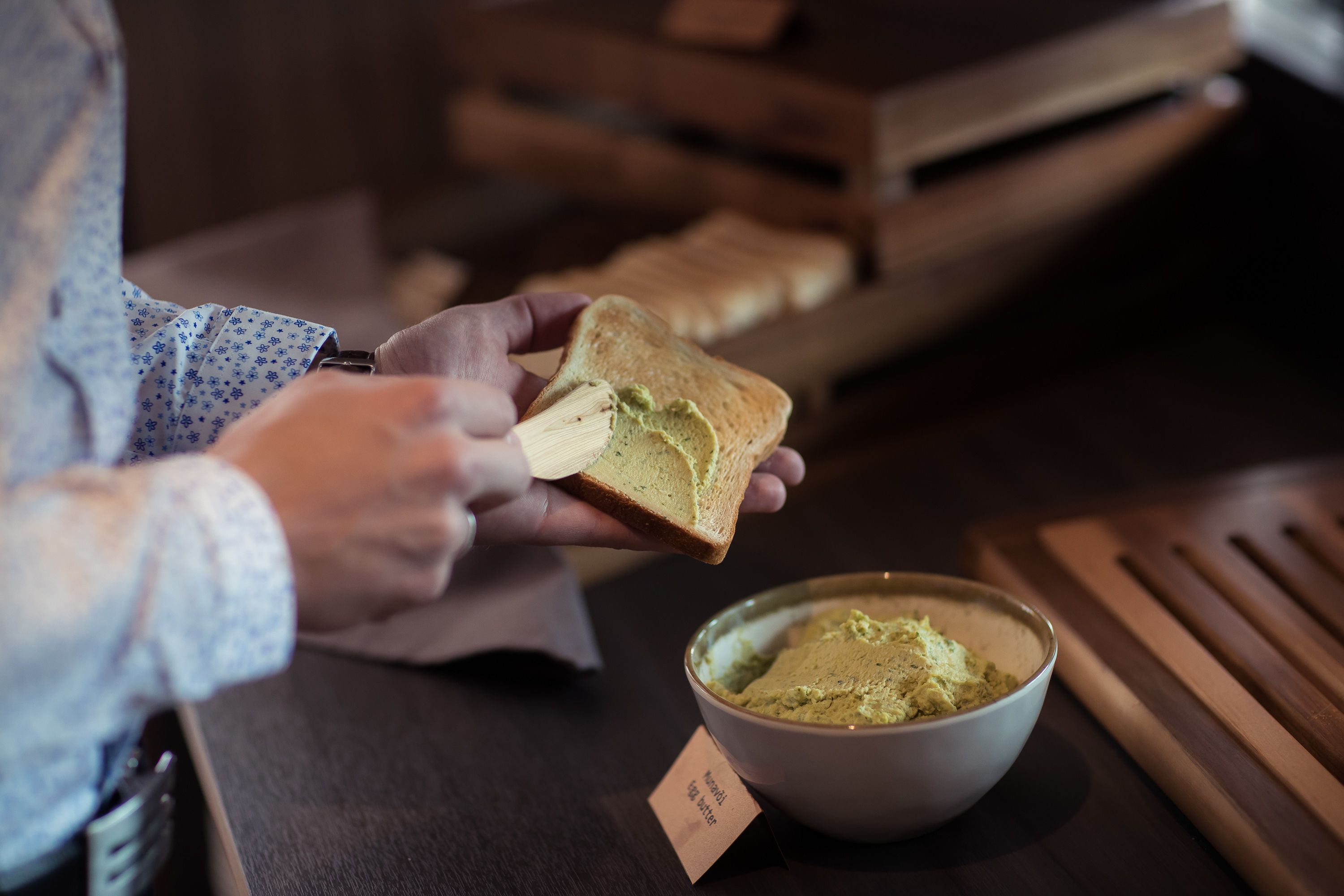 A person spreading a green substance on a slice of bread.