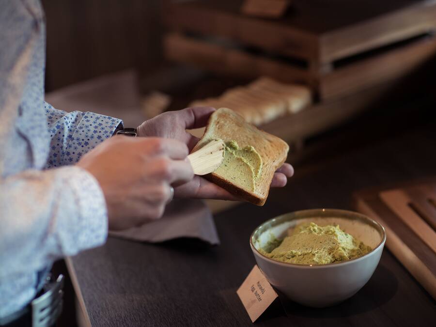 A person spreading a green substance on a slice of bread.