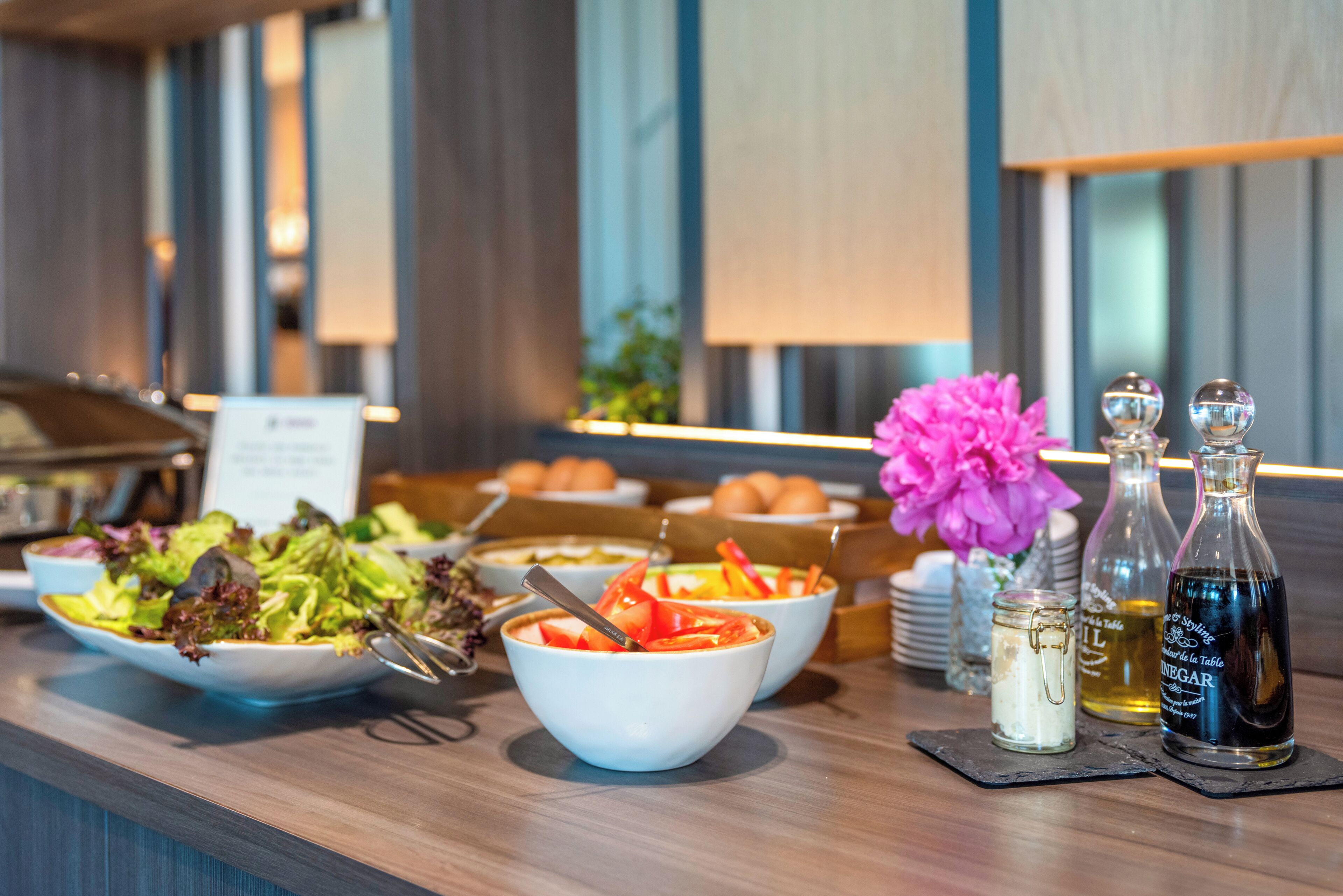 A buffet setup with various dishes, condiments, and a floral arrangement.