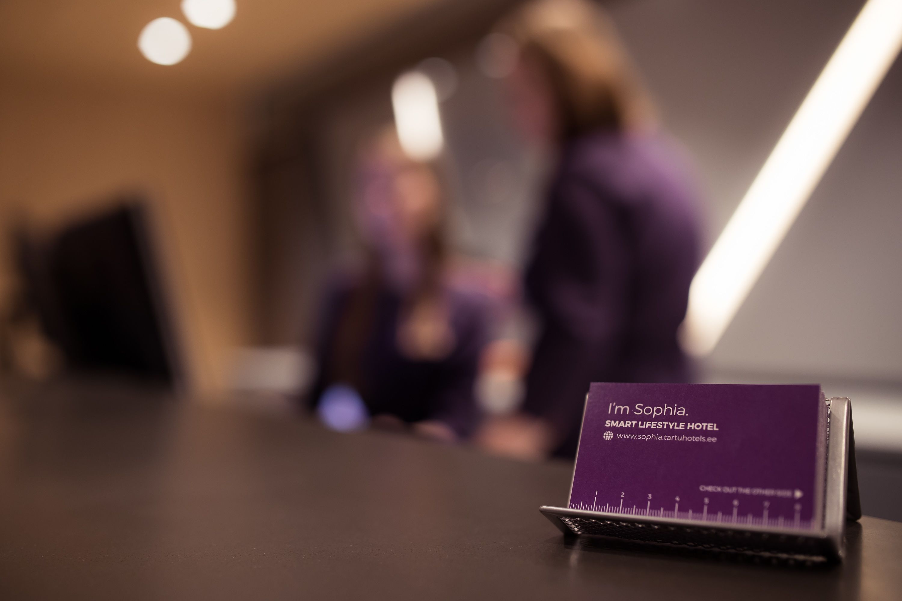 A business card on a desk with the text "I'm Sophia. SMART LIFESTYLE HOTEL."