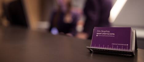 A business card on a desk with the text "I'm Sophia. SMART LIFESTYLE HOTEL."