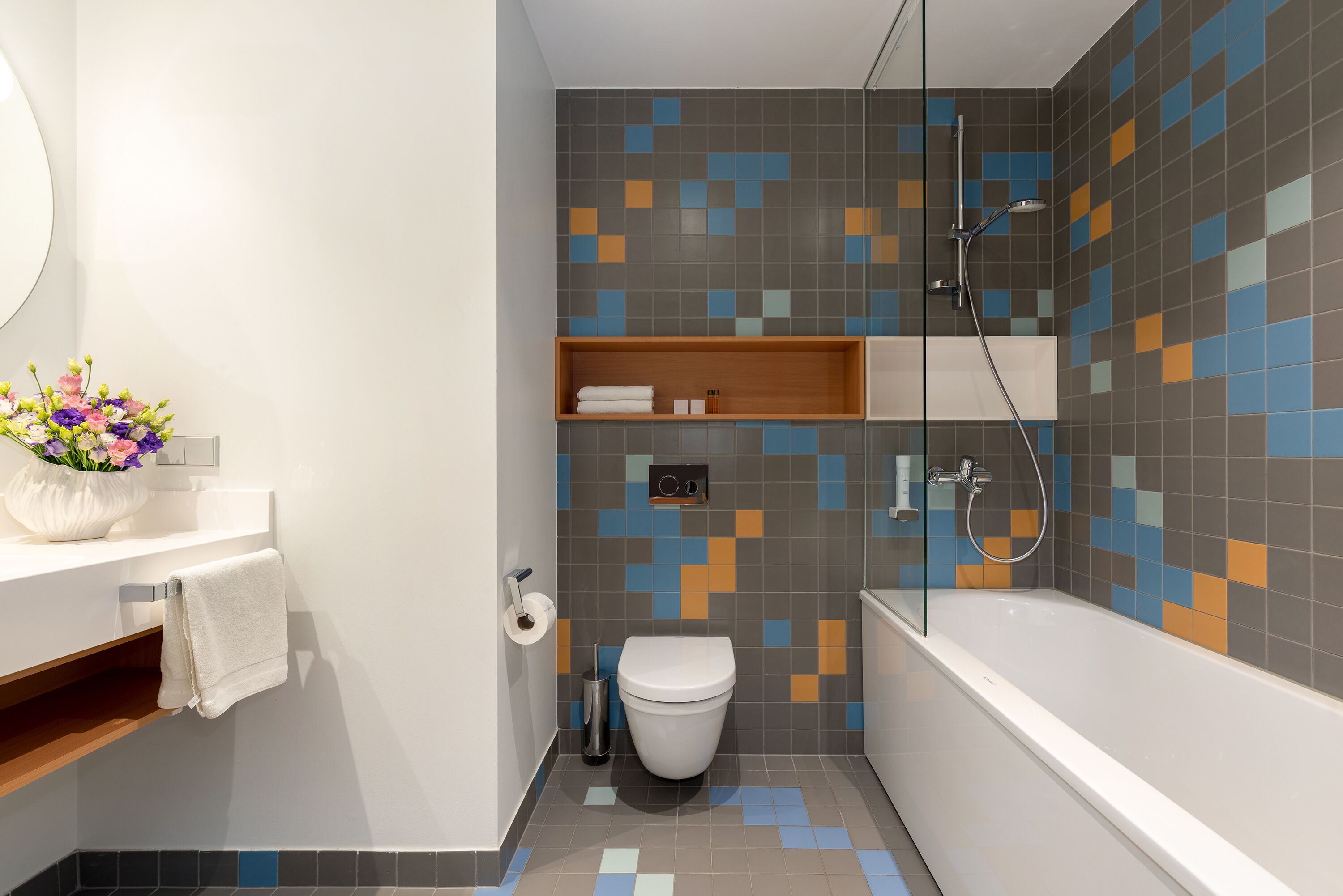 Ein modernes Badezimmer mit Toilette, Dusche und Waschtisch, dekoriert mit einem Blumenstrauß.
