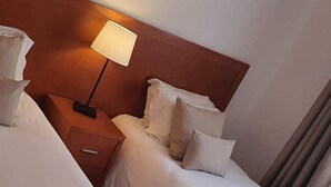 A hotel room with two beds, a nightstand with a lamp, and a wooden headboard.