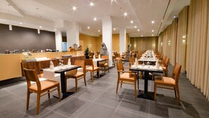 A spacious restaurant with multiple tables and chairs, a counter with a cash register, and a decorative statue. - Hotel Solar do Bom Jesus (Santa Cruz)