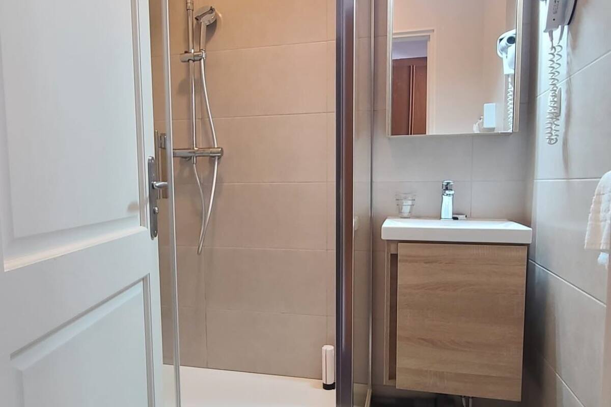 A modern bathroom with a glass shower enclosure, a wooden vanity, and a mirror above the sink.