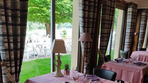 Un área de comedor con mesas dispuestas para dos, con manteles rosas y una lámpara.