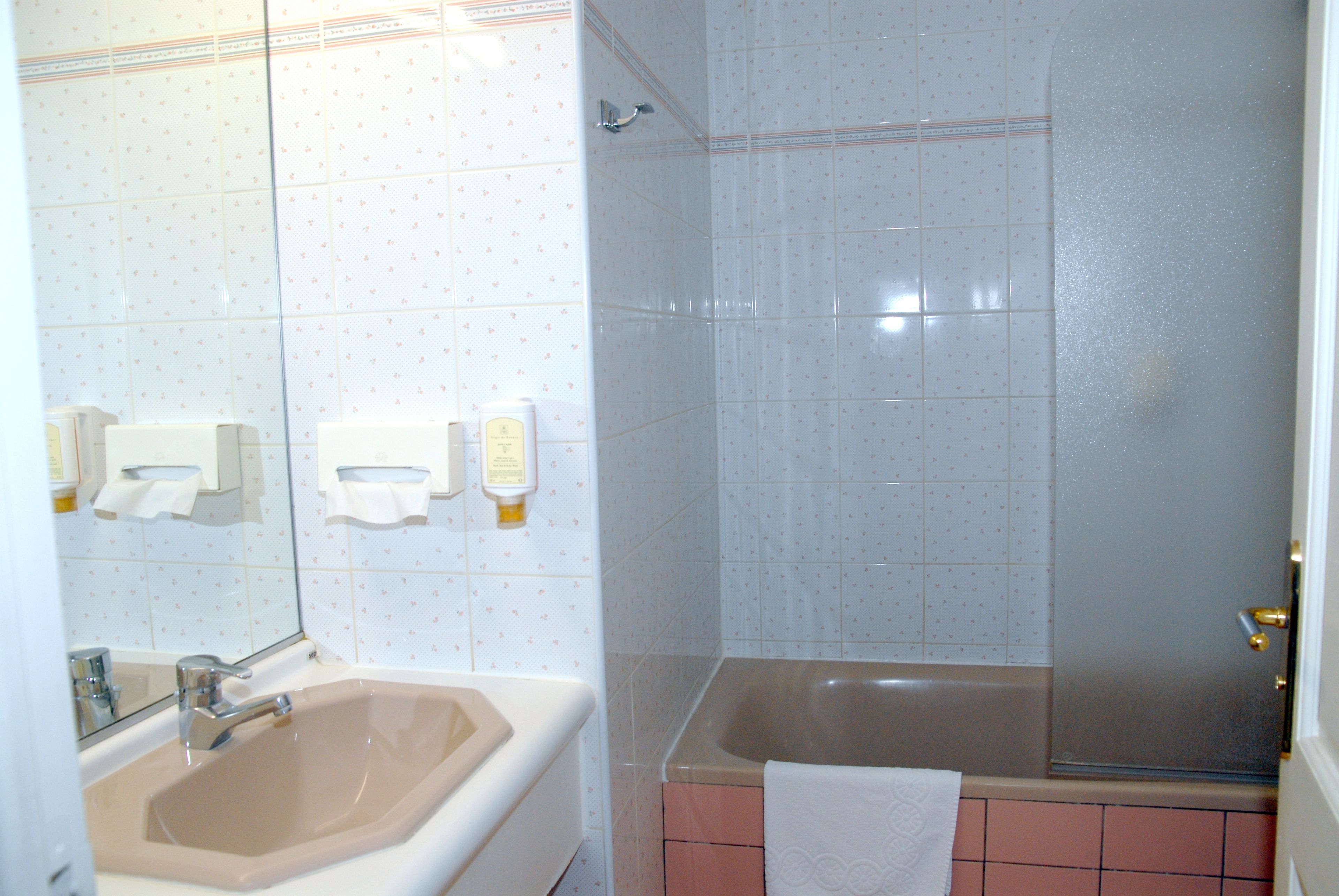 A bathroom with a sink, mirror, and a shower area.