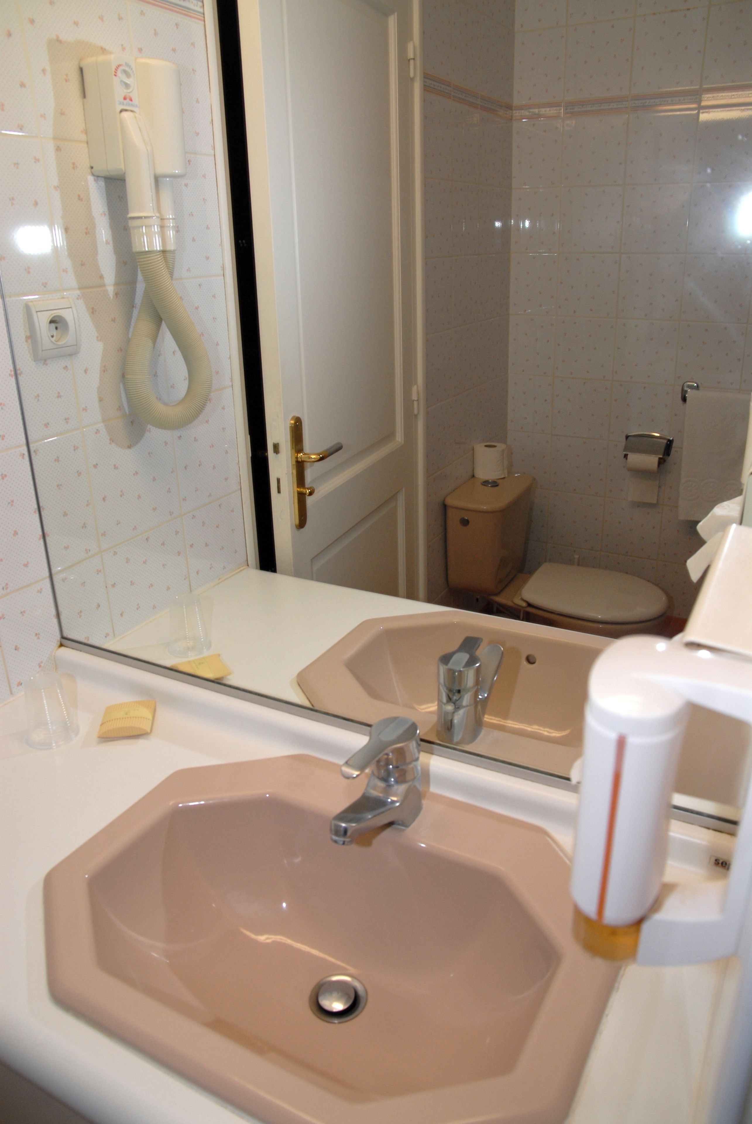 A bathroom with a sink, mirror, toilet, and shower.