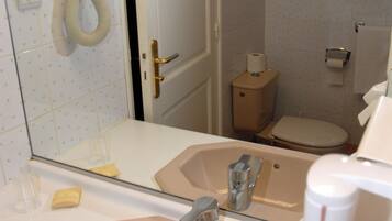 A bathroom with a sink, mirror, toilet, and shower.