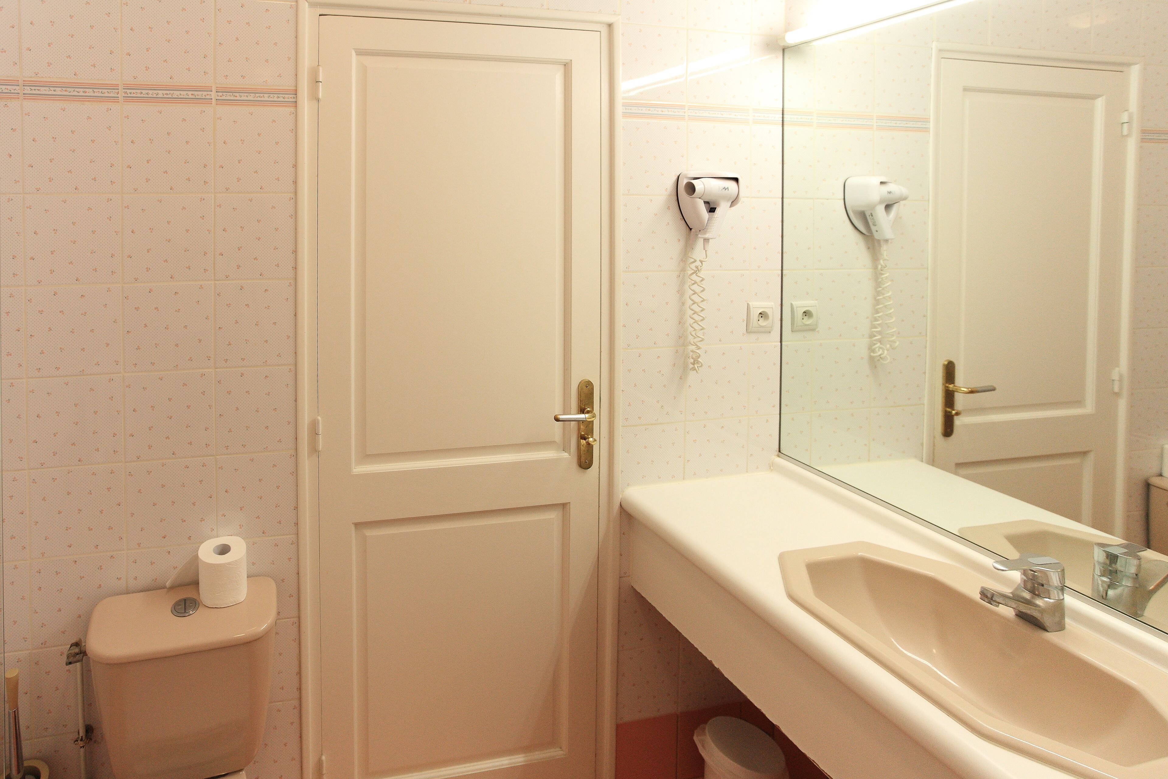Ein Badezimmer mit Toilette, Waschbecken und einem an der Wand befestigten Föhn.