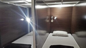 A compact room with two beds, each with a pillow and a blanket. - The Backpacker Semarang - Hostel (Semarang)