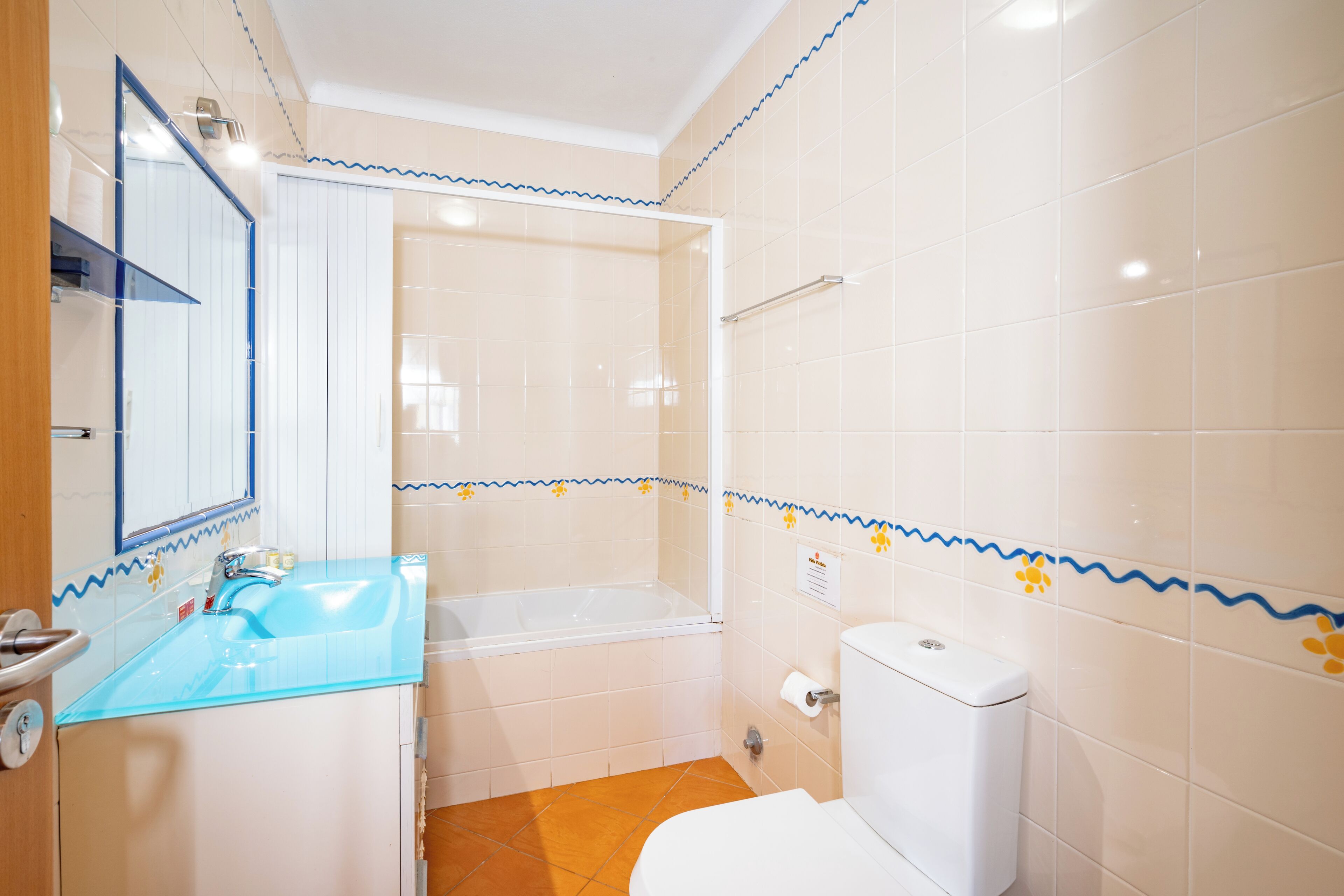 Ein Badezimmer mit einem Glaswaschbecken, einer Badewanne und einer Toilette.