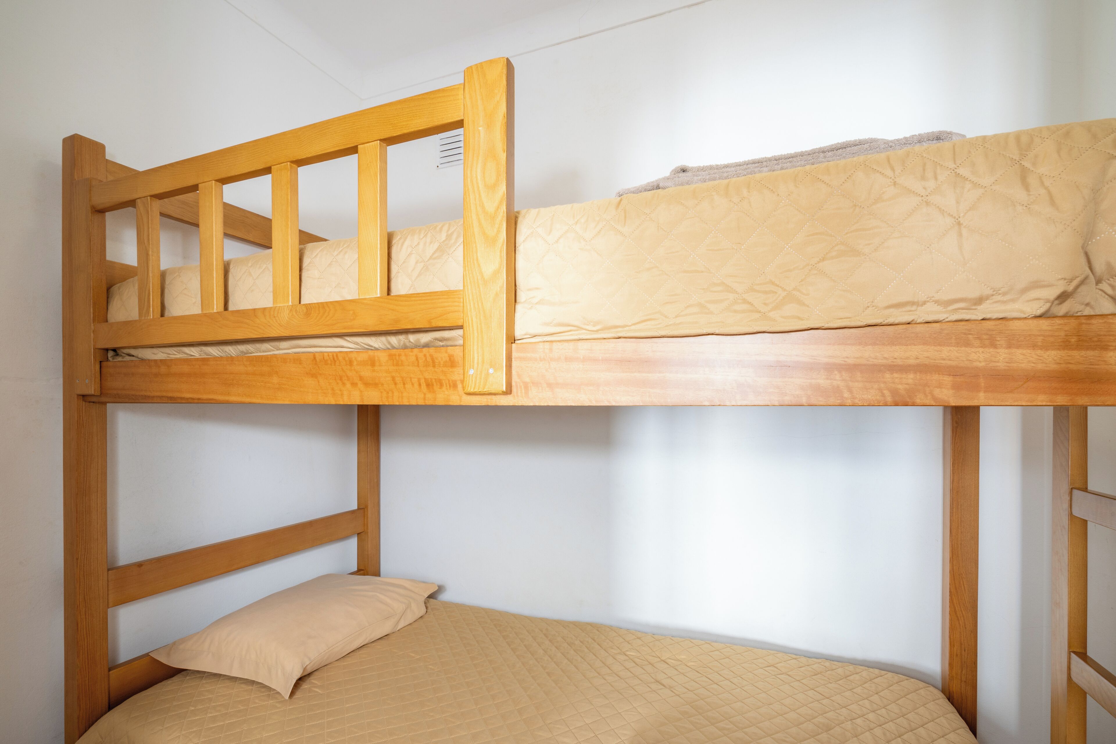 Un lit superposé avec une structure en bois et un matelas matelassé.