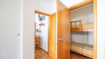 A room with a wooden door, a bunk bed, and a small table with a chair.