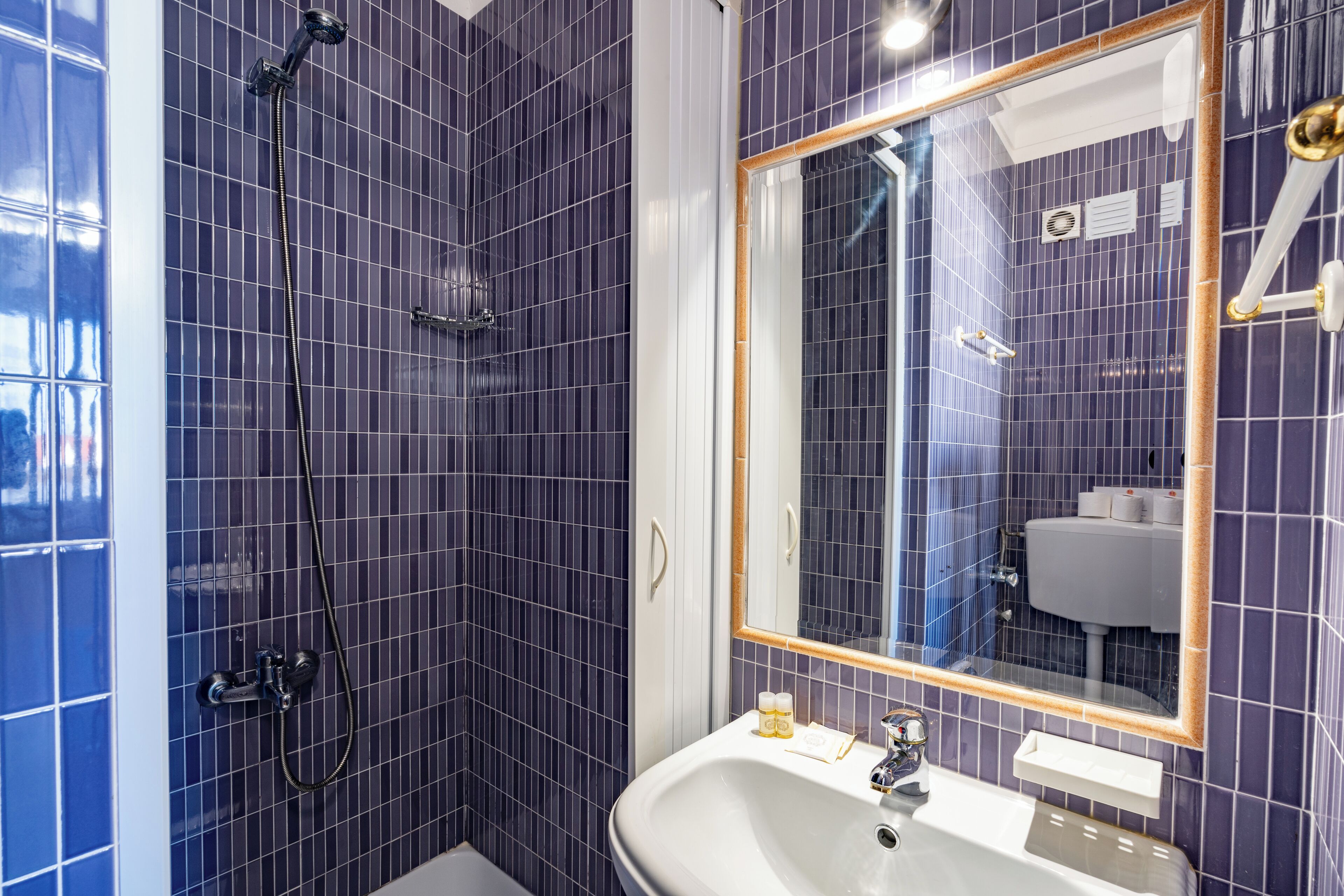 Un baño con un espejo grande, un lavamanos y una zona de ducha.
