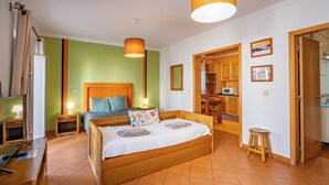 Un dormitorio con cama de madera, mesitas de noche, una lámpara, un espejo y vistas a la cocina.
