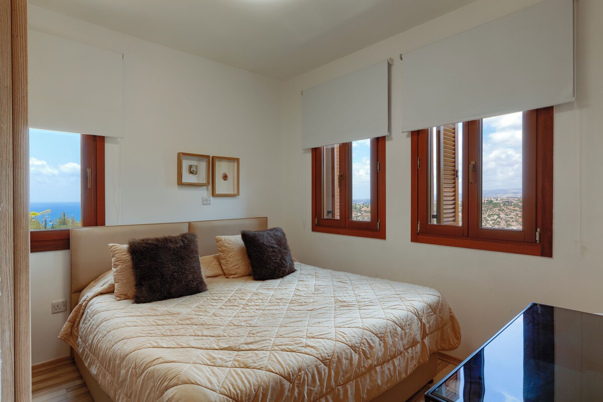 Ein Schlafzimmer mit Bett, Fernseher und Blick ins Freie.