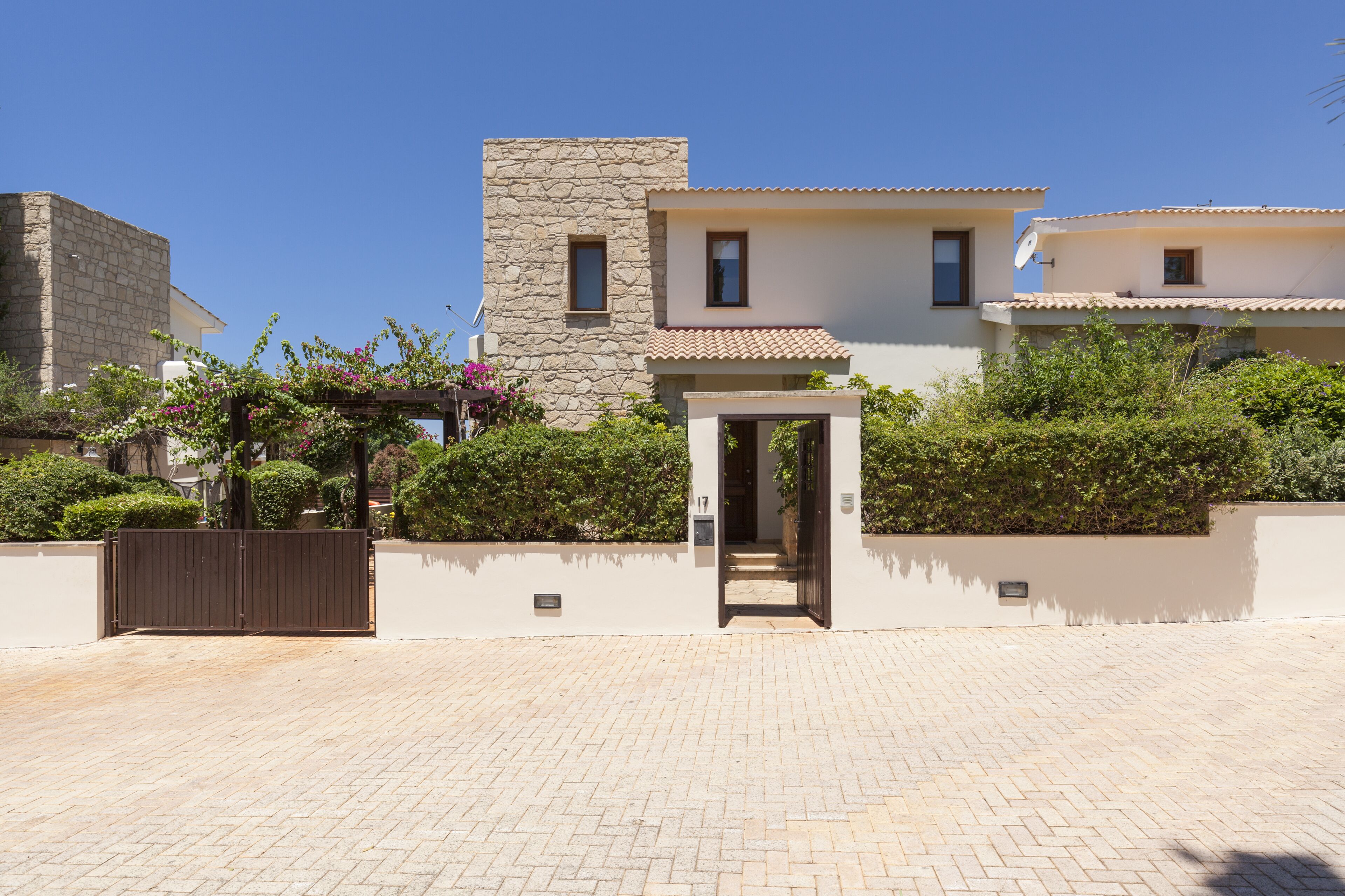 A modern house with a stone facade, a tiled roof, and a paved driveway.
