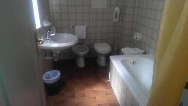A bathroom with a sink, two toilets, a trash bin, and a bathtub. - Hotel Cortina (Garda)