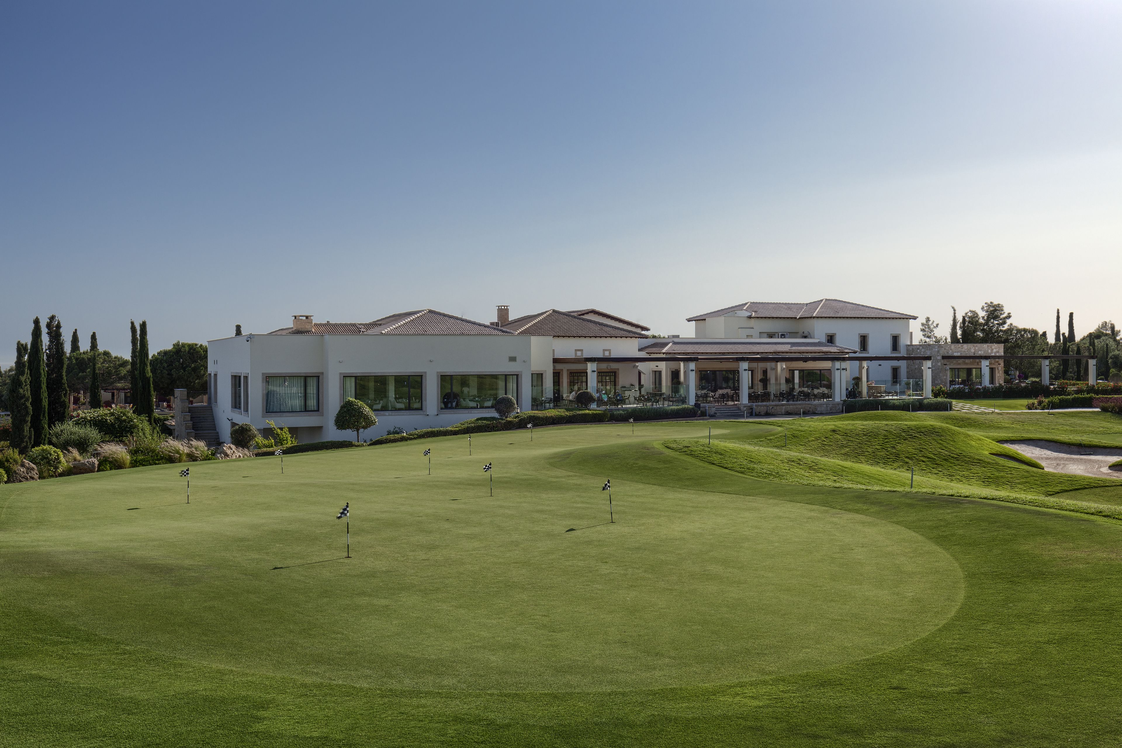 A golf course with a clubhouse and modern buildings in the background.