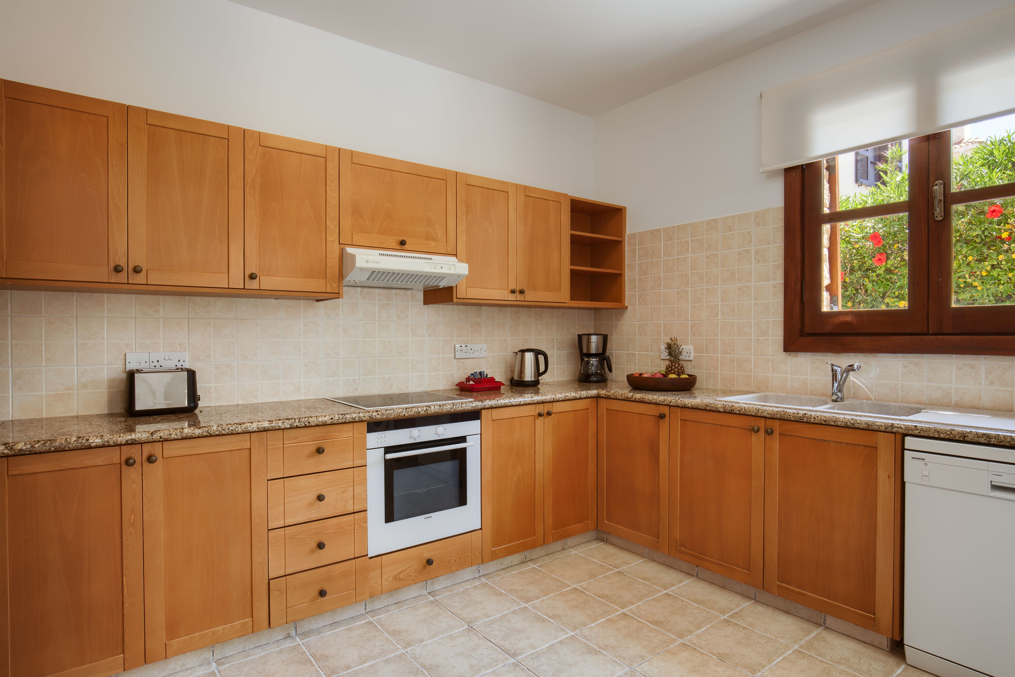 A kitchen with wooden cabinets, a built-in oven, a coffee maker, and a dishwasher.