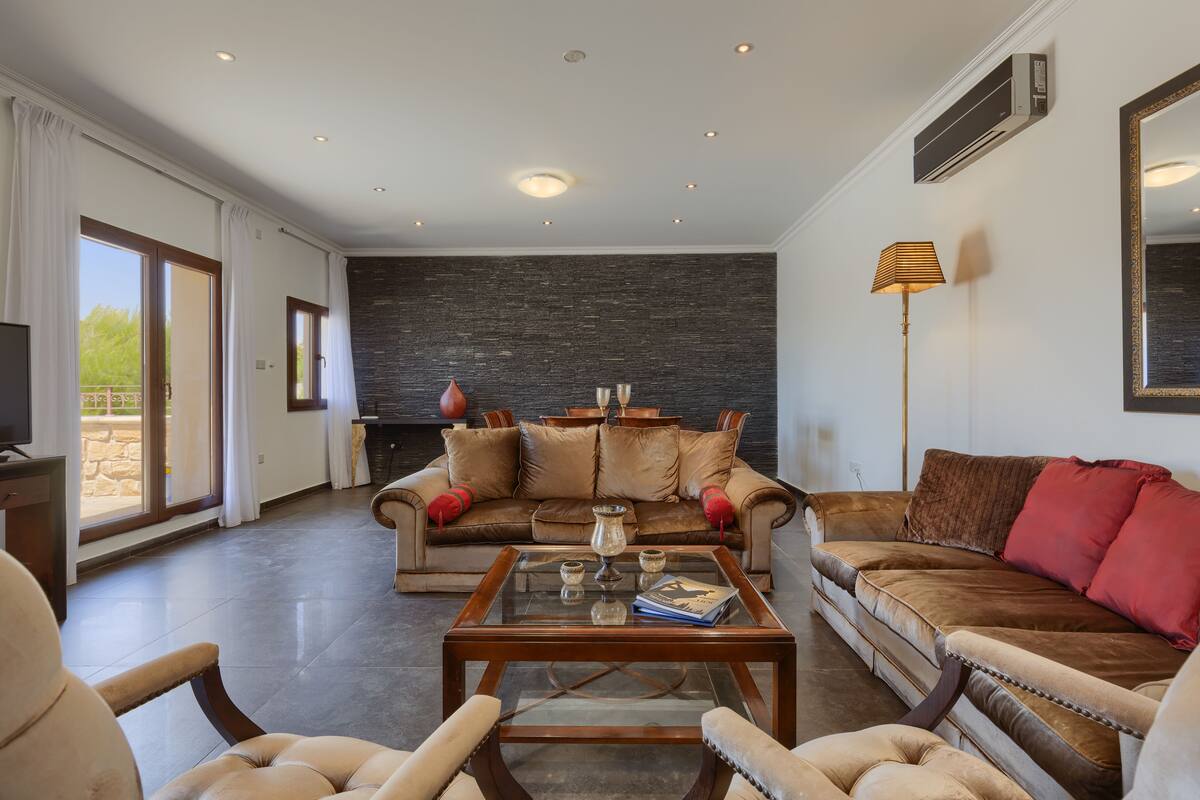A spacious living room with a large sofa set, a coffee table, and a fireplace.