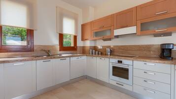 A modern kitchen with white cabinets, a built-in oven, and a coffee maker.