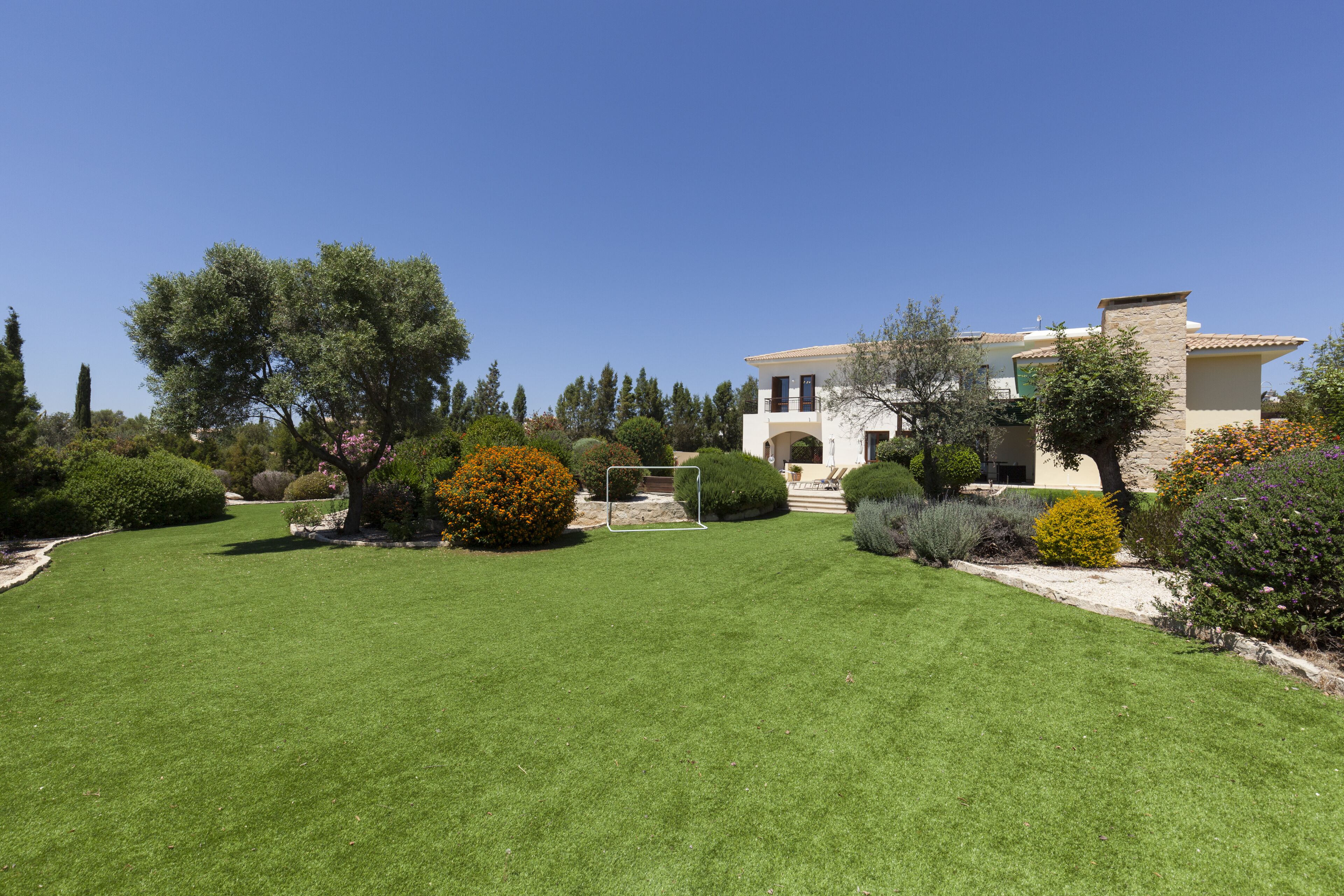 A well-maintained lawn, a house with a stone facade, and various shrubs and trees.