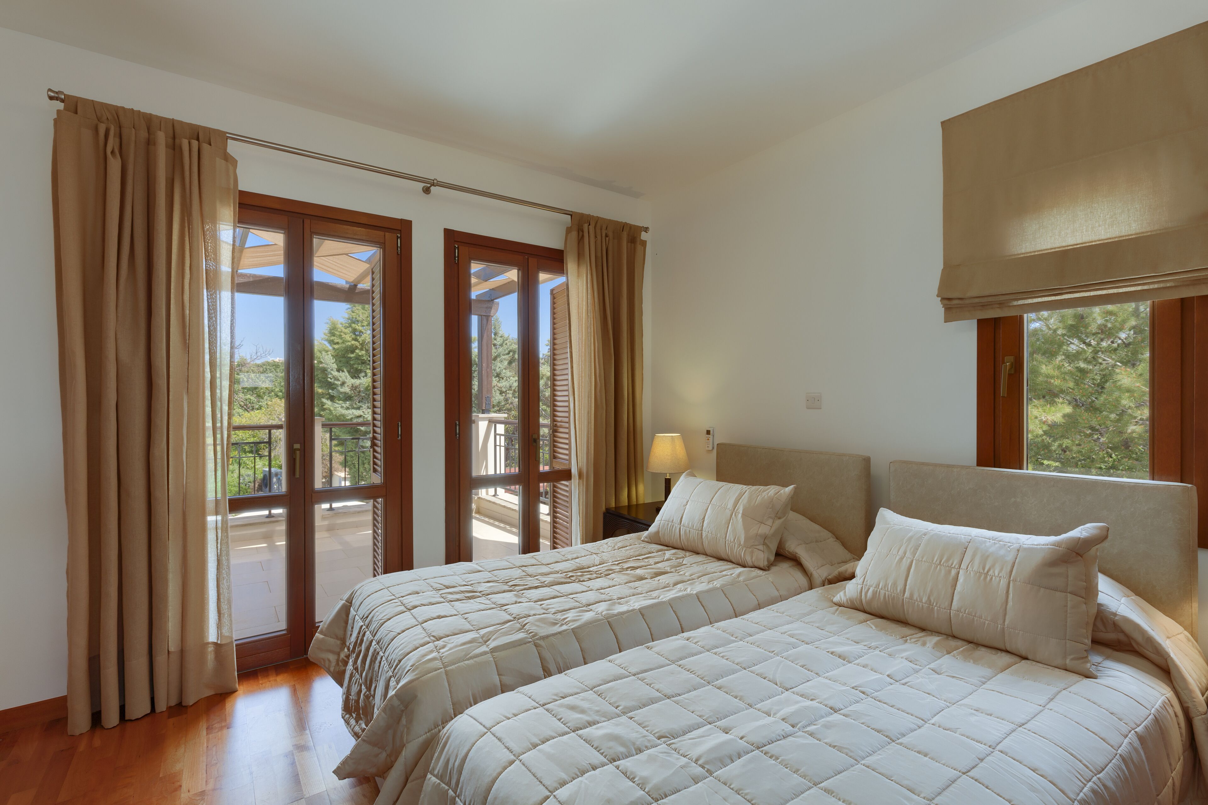 Una camera da letto con due letti, un balcone e vista sul verde.