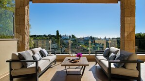 A balcony with two sofas, a coffee table, and a view of a cityscape. - Aphrodite Hills Rentals – Superior Villas (Kouklia)
