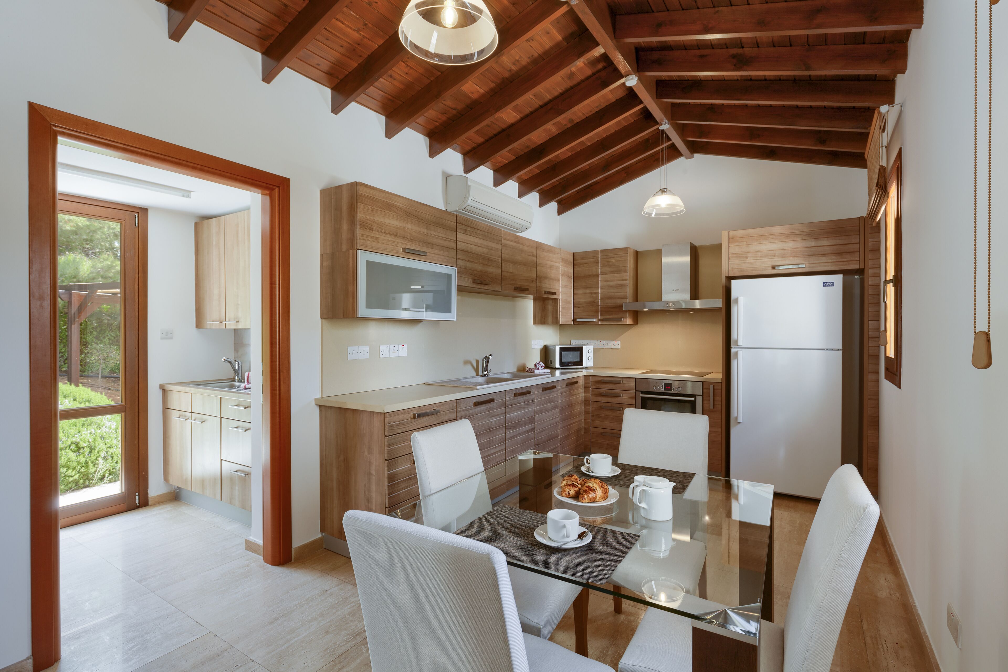 A modern kitchen with wooden cabinets, a glass dining table, and a built-in microwave.