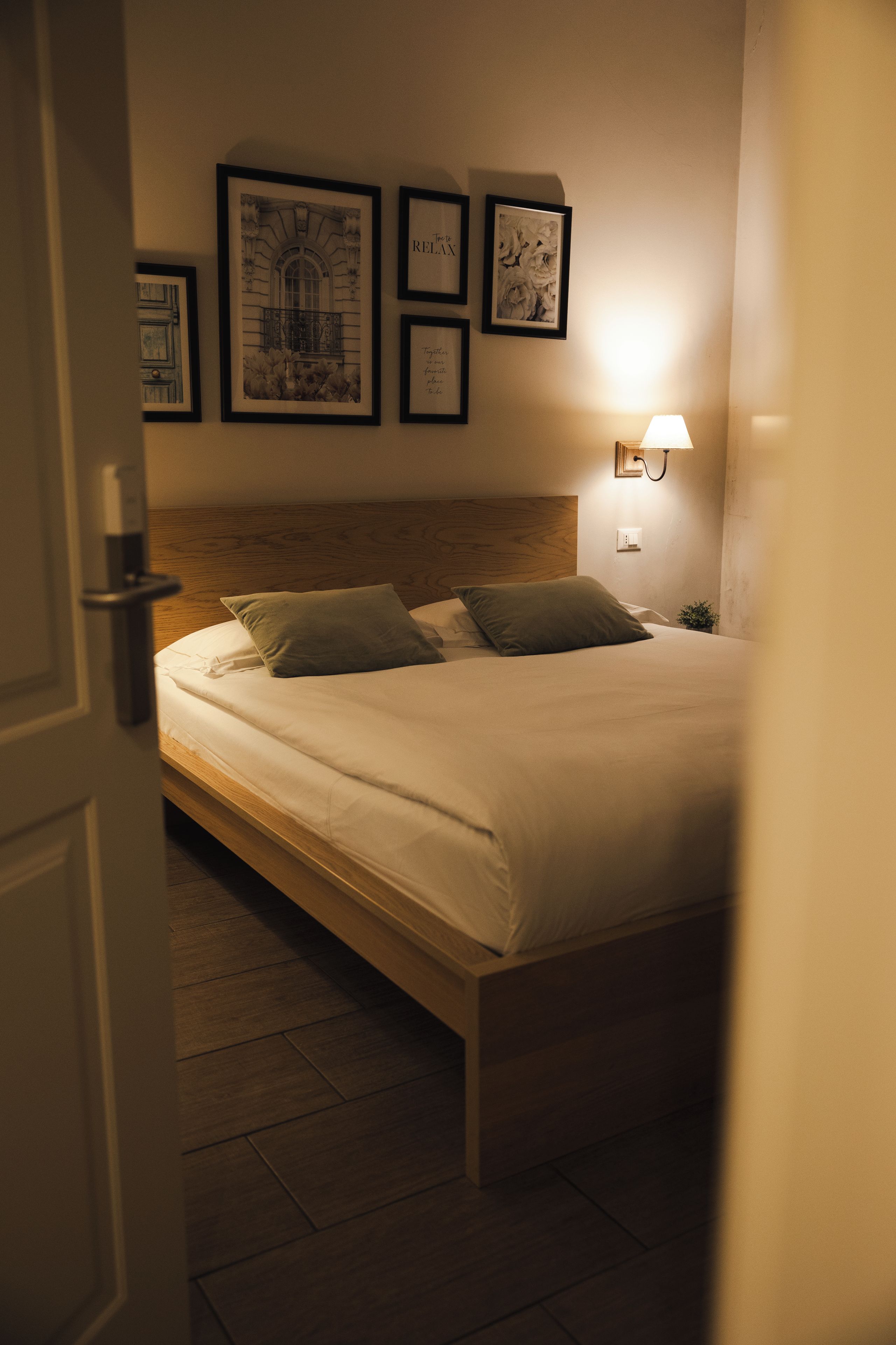 A bedroom with a bed, a headboard, a nightstand, and a wall-mounted lamp.