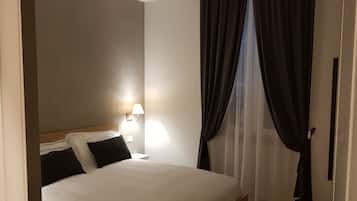Ein Hotelzimmer mit einem Bett, einem Nachttisch, einer Lampe und transparenten Vorhängen.