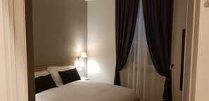 A hotel room with a bed, a nightstand, a lamp, and sheer curtains. - Bed Milano Linate (Milan)