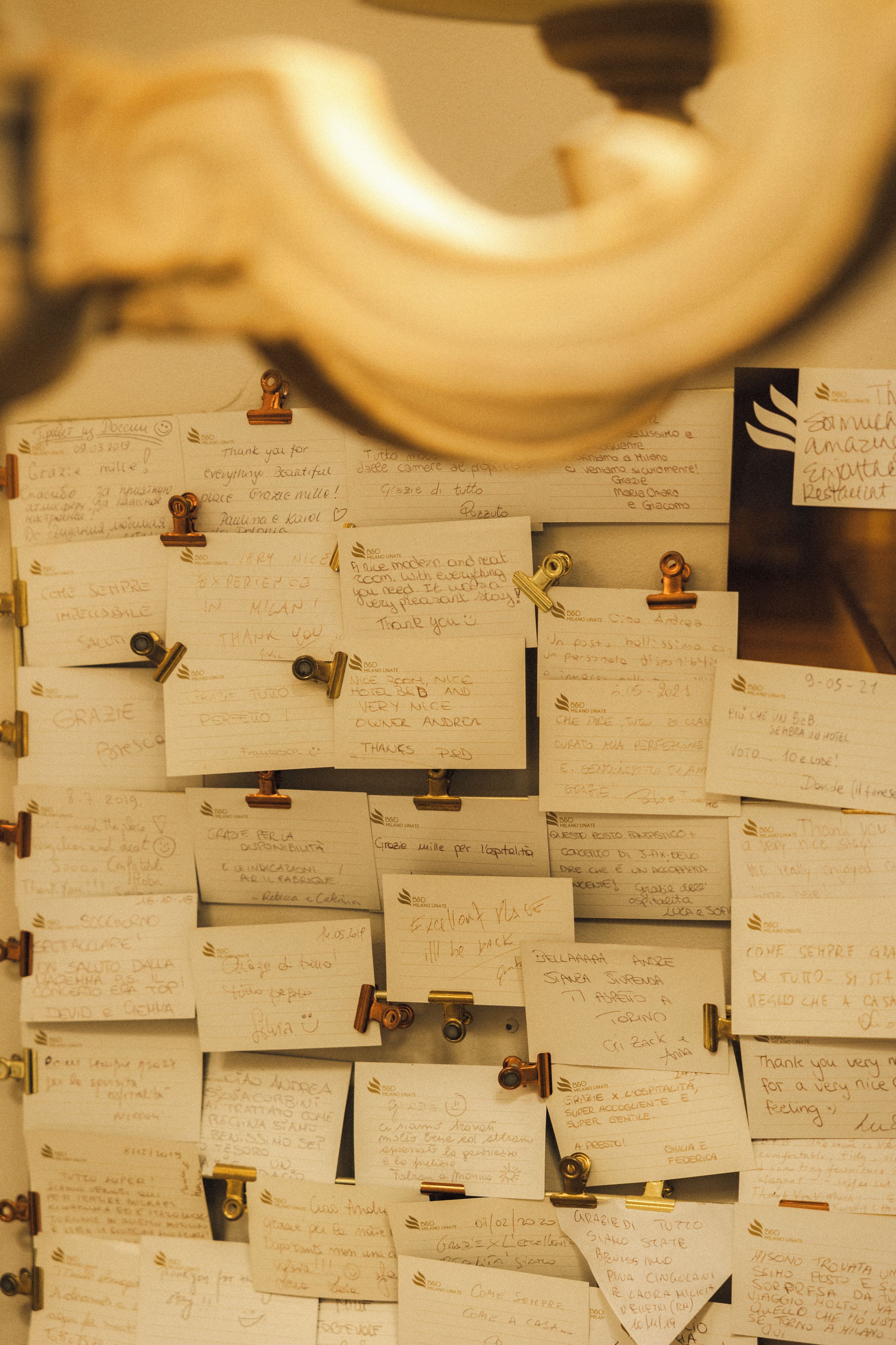 Un mur recouvert de notes manuscrites, fixées à l’aide d’agrafes métalliques, qui contiennent probablement des commentaires ou des suggestions des clients.
