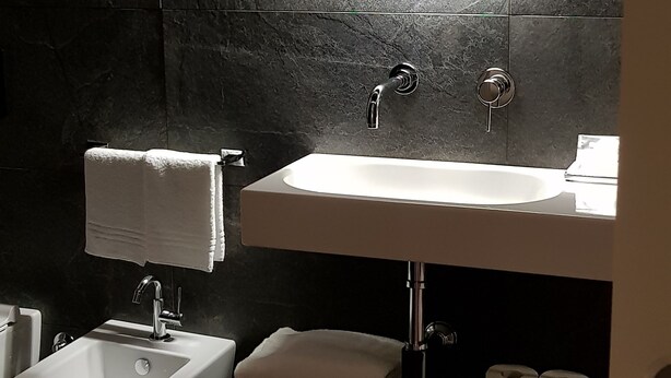 A modern bathroom with a round mirror, a sink, a bidet, and a toilet. - Bed Milano Linate (Milan)