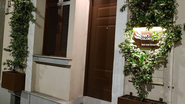 Entrada de hotel con un letrero de 'Bed and Breakfast', un letrero de 'Foresteria' y plantas en macetas.