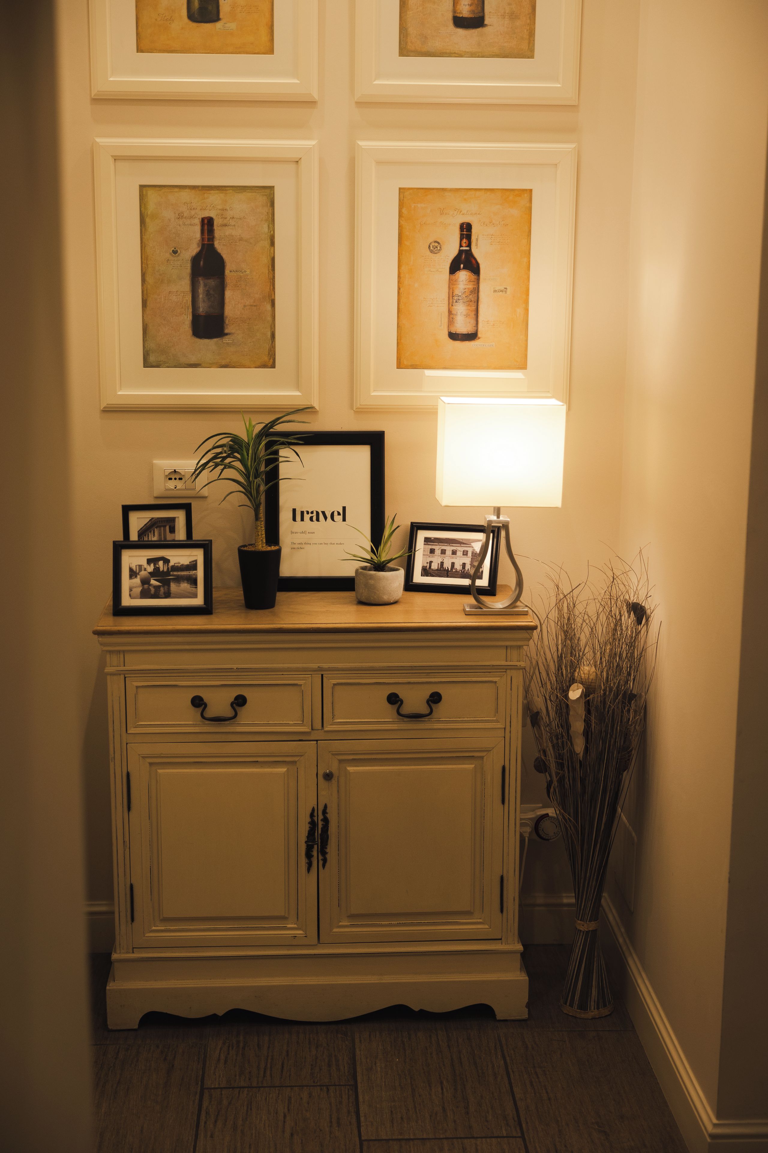 A wall with framed artwork, a potted plant, a framed picture, and a lamp.