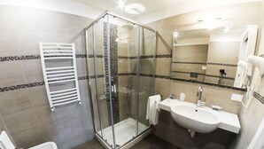 Un baño moderno con ducha acristalada, lavamanos blanco y un bidé.