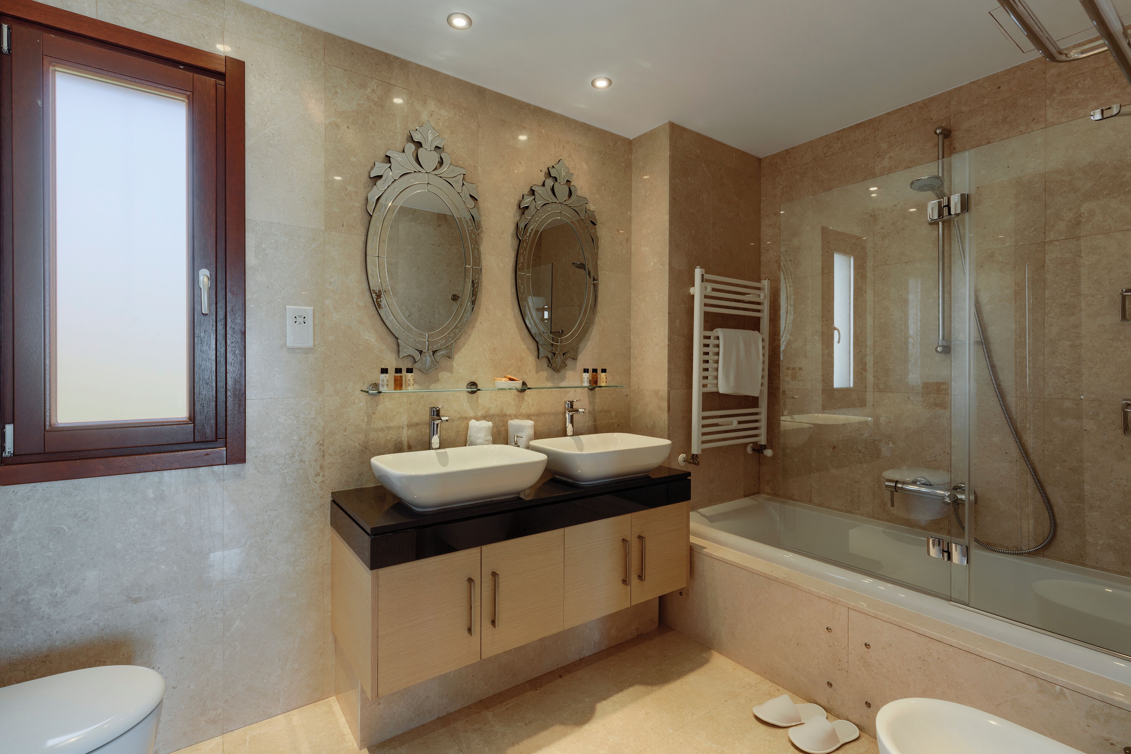 Une salle de bain moderne avec deux lavabos, une douche à parois de verre et un grand miroir au-dessus des lavabos.
